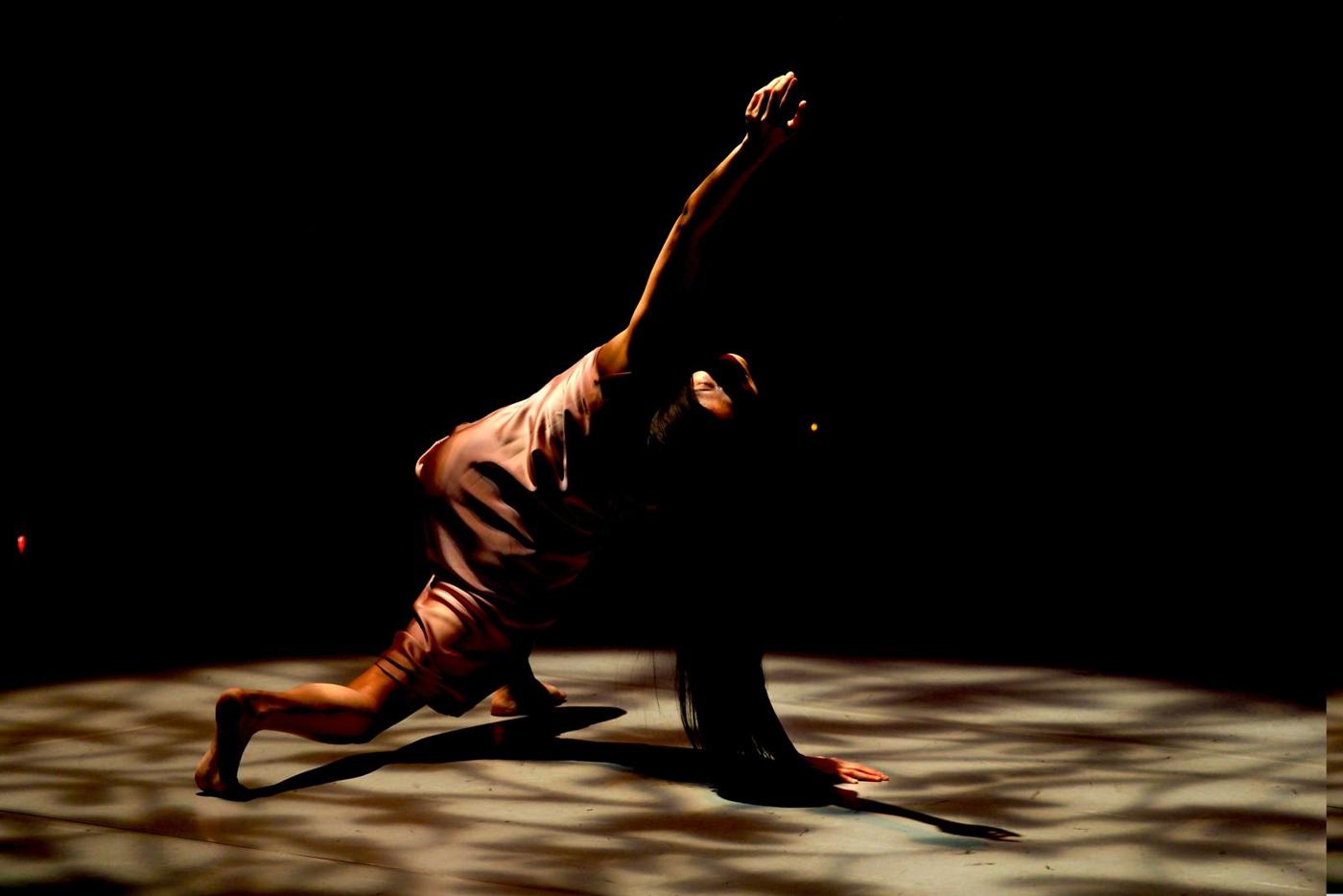 A dancer leaping across a darkened stage