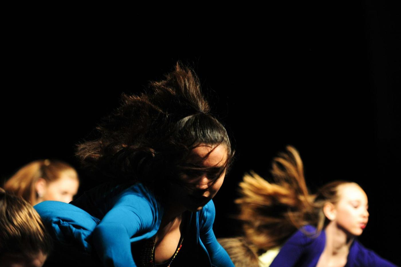 Dancers mid-movement under stage light