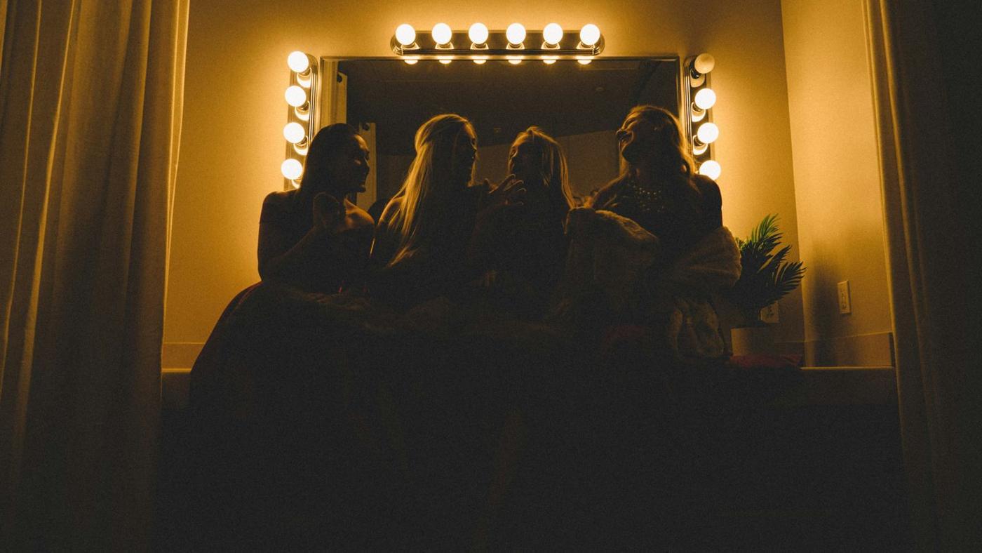Silhouetted figures in front of a wall of warm dressing-room lights