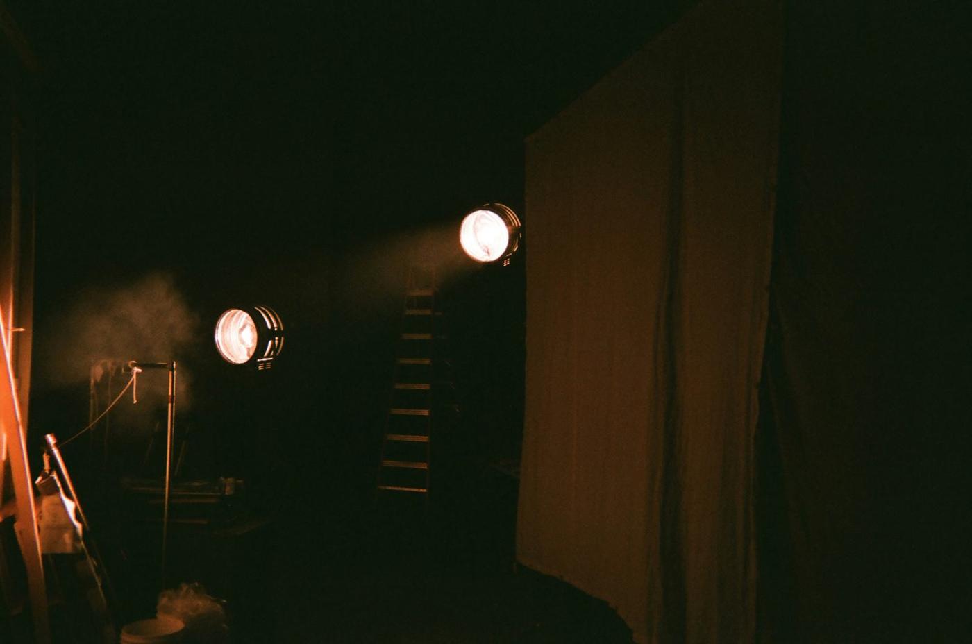 A dark stage lit by two practical lamps