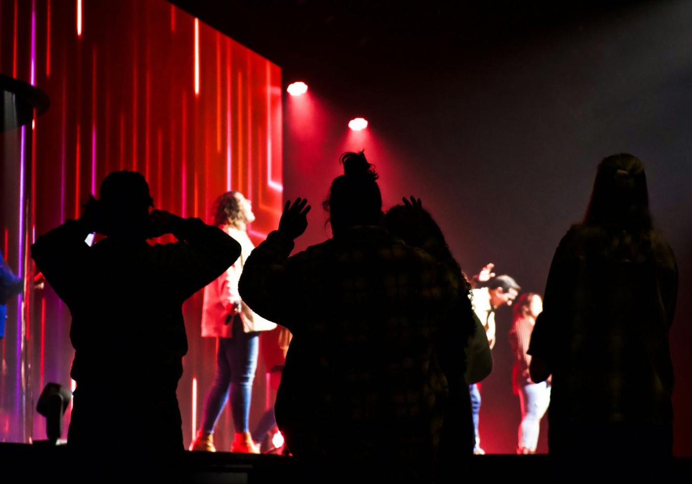 Figures silhouetted against red stage light